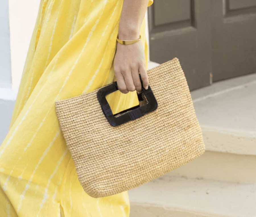 19 Fresh FINDS Around BHAM: Closet Refreshers, Entertaining Picks & More - 3 A person wearing a yellow dress holds a rectangular woven straw clutch bag with a black handle.