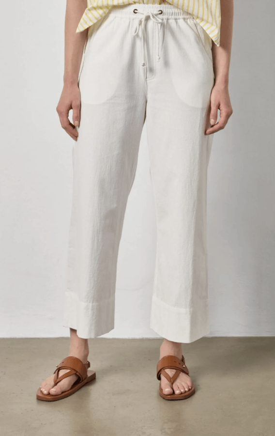 19 Fresh FINDS Around BHAM: Closet Refreshers, Entertaining Picks & More - 6 Person wearing off-white wide-leg drawstring pants, a yellow and white striped top, and brown sandals standing on a light-colored floor against a plain wall.