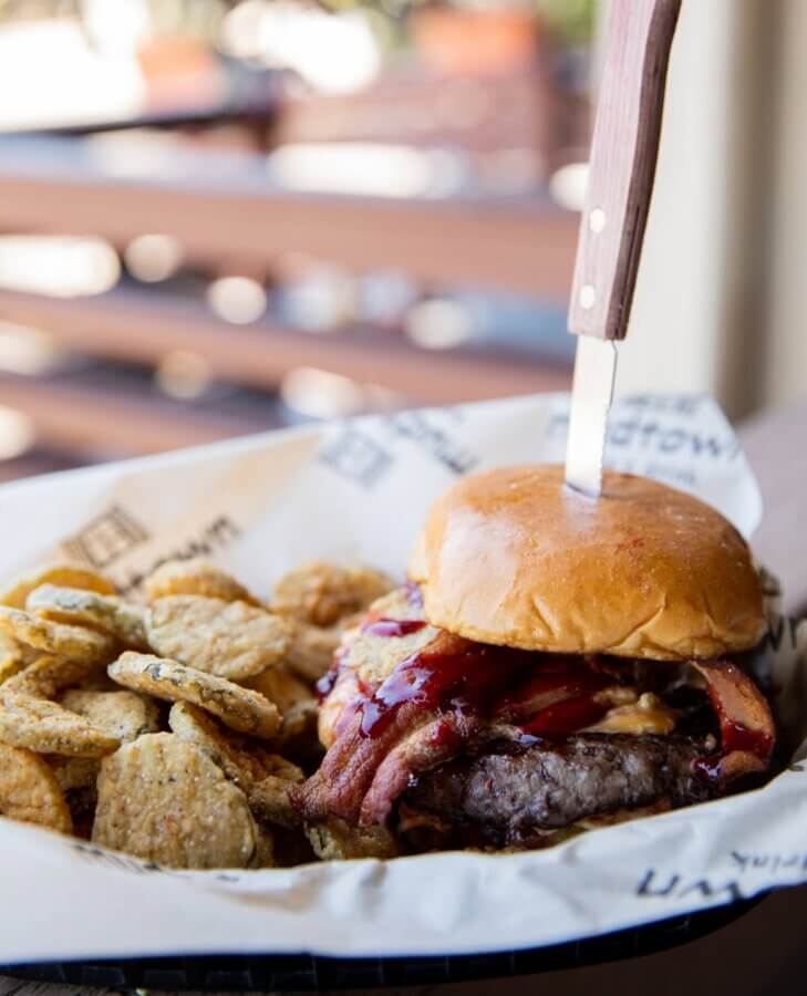 11 Must-Try Burgers in Birmingham - 9 A BHAM must-try, this burger with sauce, bacon, and a knife through the bun is served in a basket alongside crispy fried pickles at Mudtown.