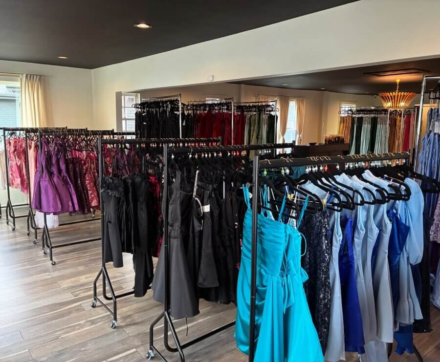 10 New Retail Spots to Check Out in BHAM (+1 Coming Soon!) - 4 Racks of formal dresses in various colors and styles are displayed in a well-lit boutique with wood flooring and neutral walls — a chic new retail spot in BHAM.