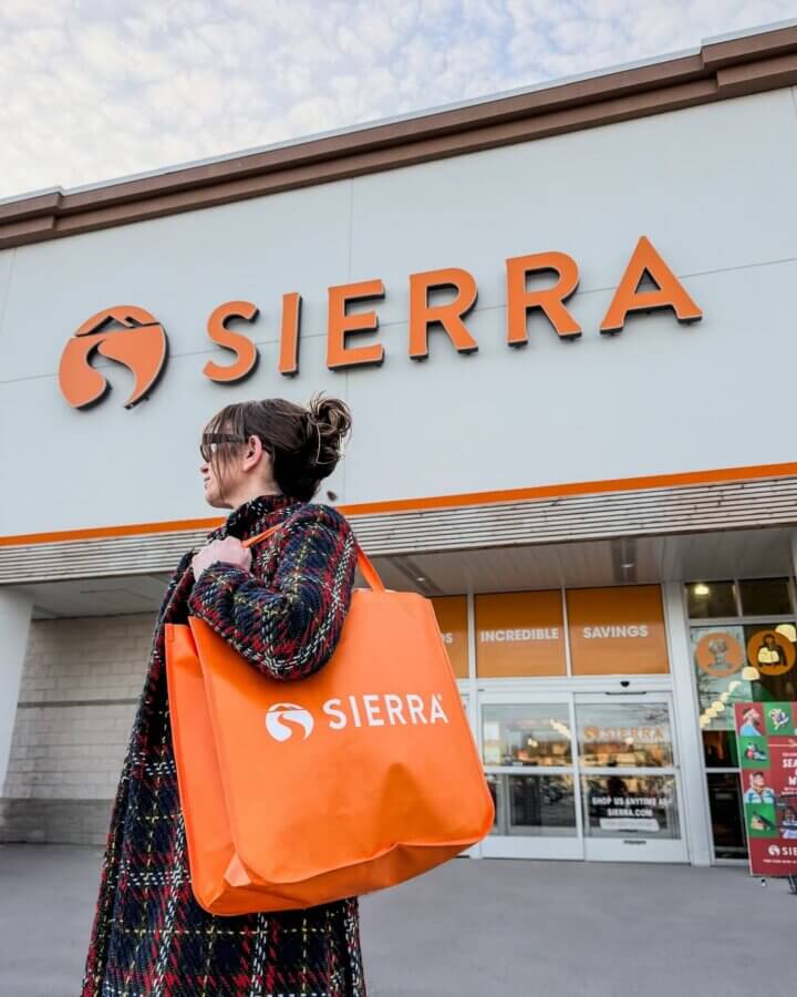 10 New Retail Spots to Check Out in BHAM (+1 Coming Soon!) - 12 A person with glasses carries an orange Sierra shopping bag outside a new Sierra retail spot, with the store's logo visible above the entrance.