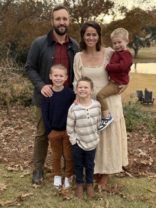 The Baker Everyone in Bluff Park Is Talking About - 6 The Nuss family poses outdoors; two adults stand behind three young boys, with one child held by the woman. All are smiling in casual fall clothing, sharing a joyful moment.