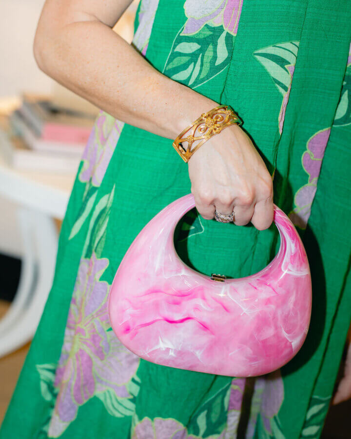 3 BHAM Boutiques Share Their Favorite Spring 2026 Looks - 3 A person wearing a green floral dress and gold bracelet holds a pink marbled handbag, capturing one of our Favorite Spring looks from BHAM Boutiques.
