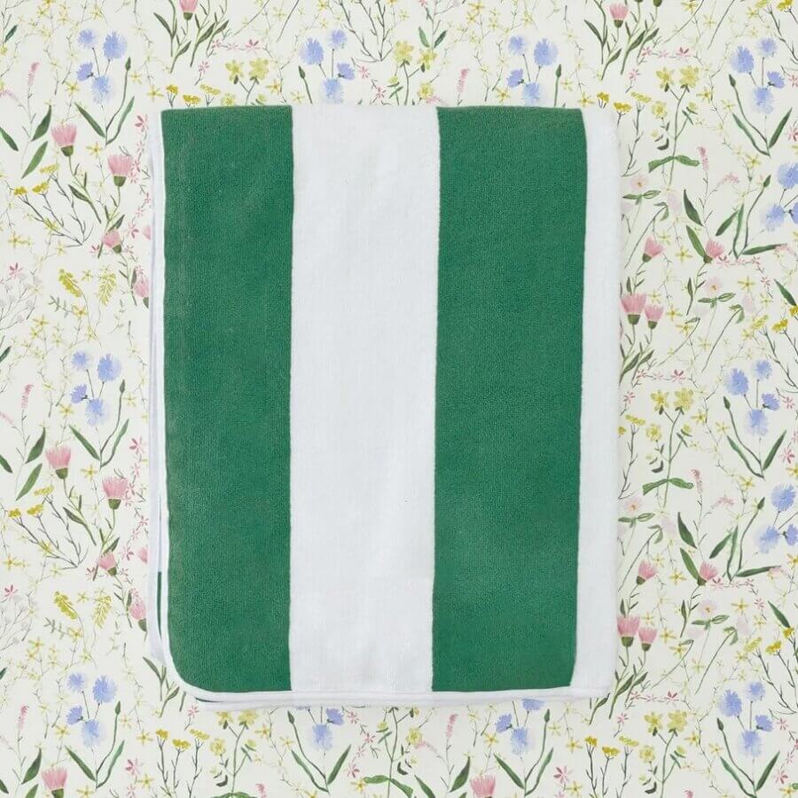 18 Nashville FINDS We're Loving This Month - 18 A neatly folded towel with green and white vertical stripes, part of the FINDS Draft collection, placed on a floral-patterned surface.