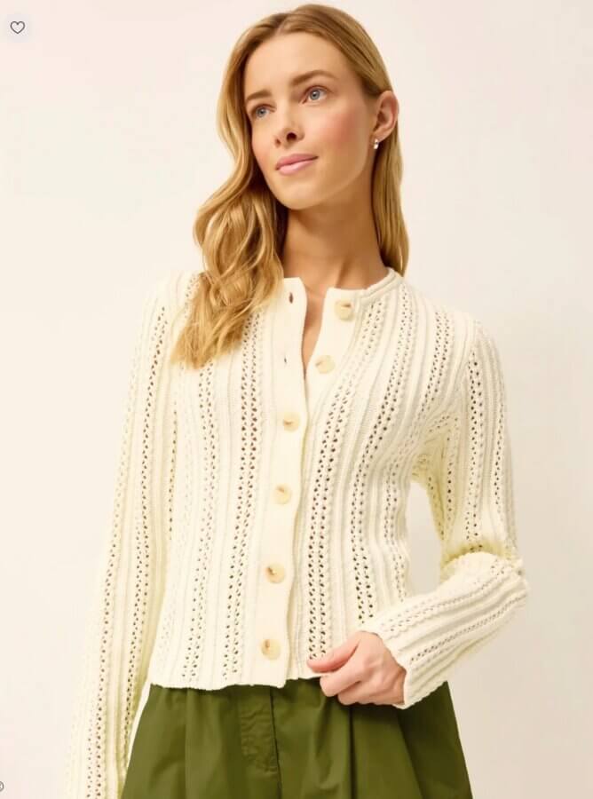18 Nashville FINDS We're Loving This Month - 5 Woman wearing a cream-colored, buttoned, knit cardigan with vertical patterns and olive green skirt, standing against a plain light background. Perfect for March 2026 style inspiration from the FINDS Draft collection.