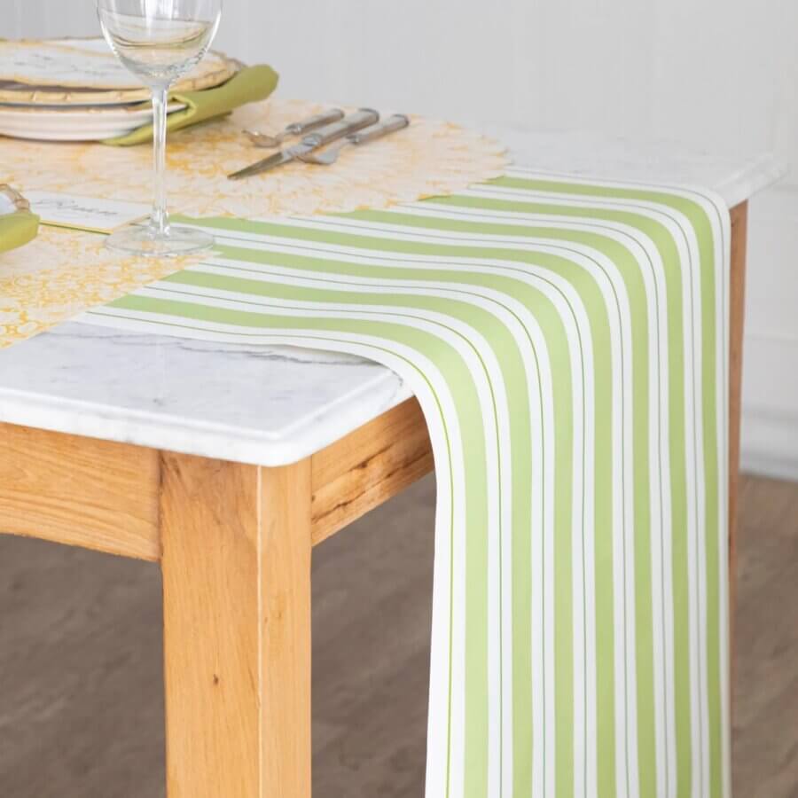 18 Nashville FINDS We're Loving This Month - 13 A green and white striped table runner drapes over the edge of a wooden table, set for a cozy March 2026 gathering with plates, wine glasses, and a yellow patterned placemat—perfect inspiration for your next FINDS Draft.