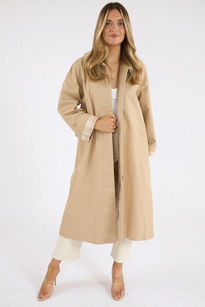 18 Nashville FINDS We're Loving This Month - 3 Woman wearing a long beige coat over a white outfit, standing against a plain white background—an elegant look from the FINDS Draft, March 2026 collection.