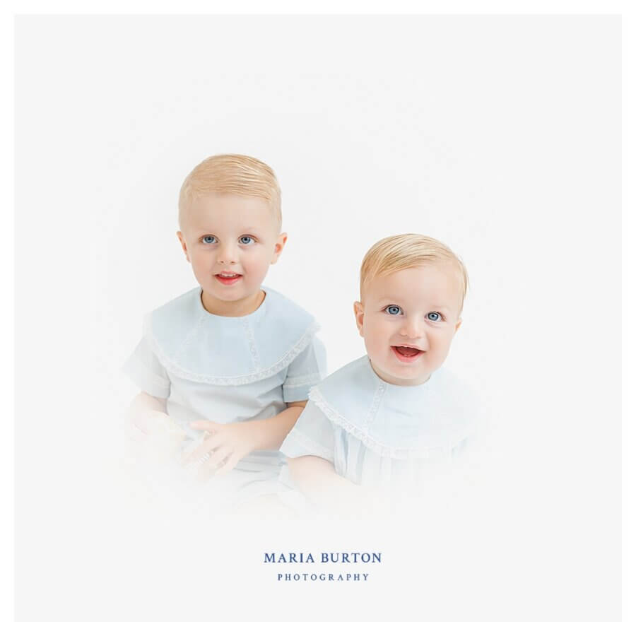 Heirloom Portraits Are Making a Comeback! - 6 Two young children with blonde hair, wearing matching light blue outfits, sit side by side against a white background in the timeless style favored by Southern heirloom portrait photographers.