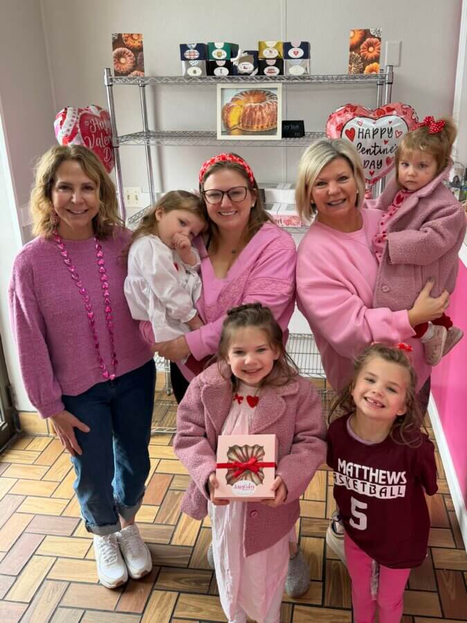 Meet the Sisters Behind Louisville’s SissyCakes Bakery - 5 Six people, including three adults and three children, stand smiling indoors in Louisville. Most wear pink or red clothing, with Valentine’s Day decorations and SissyCakes treats.