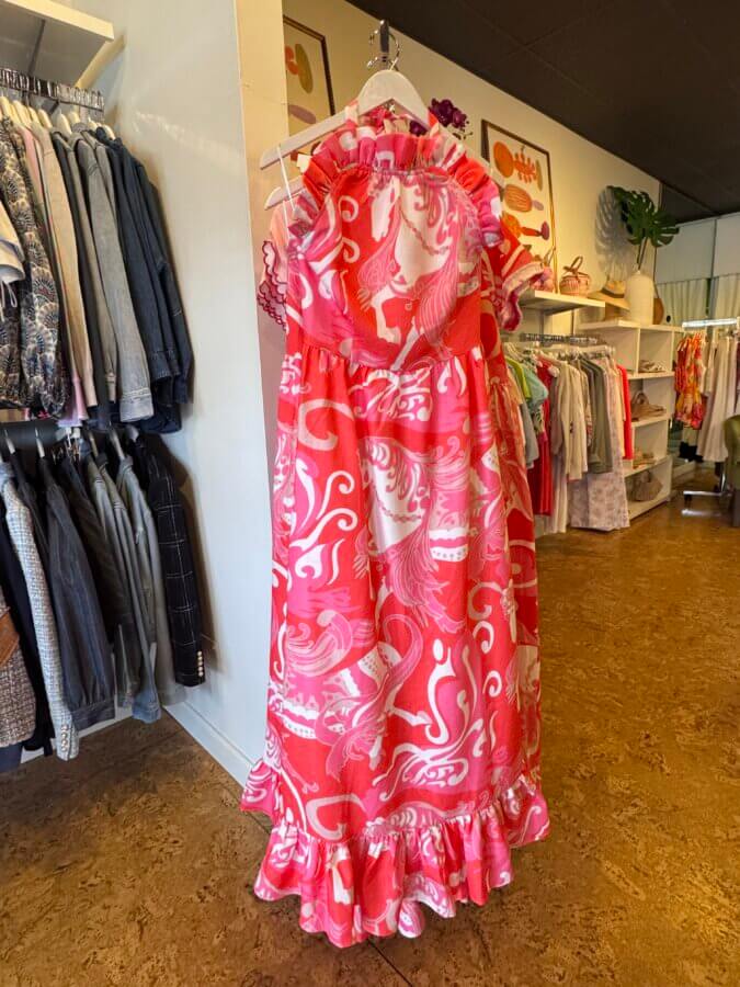 16 Louisville FINDS for April: Spring Style, Derby-Ready Decor & Must-Have Gifts - 4 A pink and white ruffled dress with a bold horse and swirl print, perfect for spring, hangs on a rack among unique Louisville finds in a boutique clothing store.