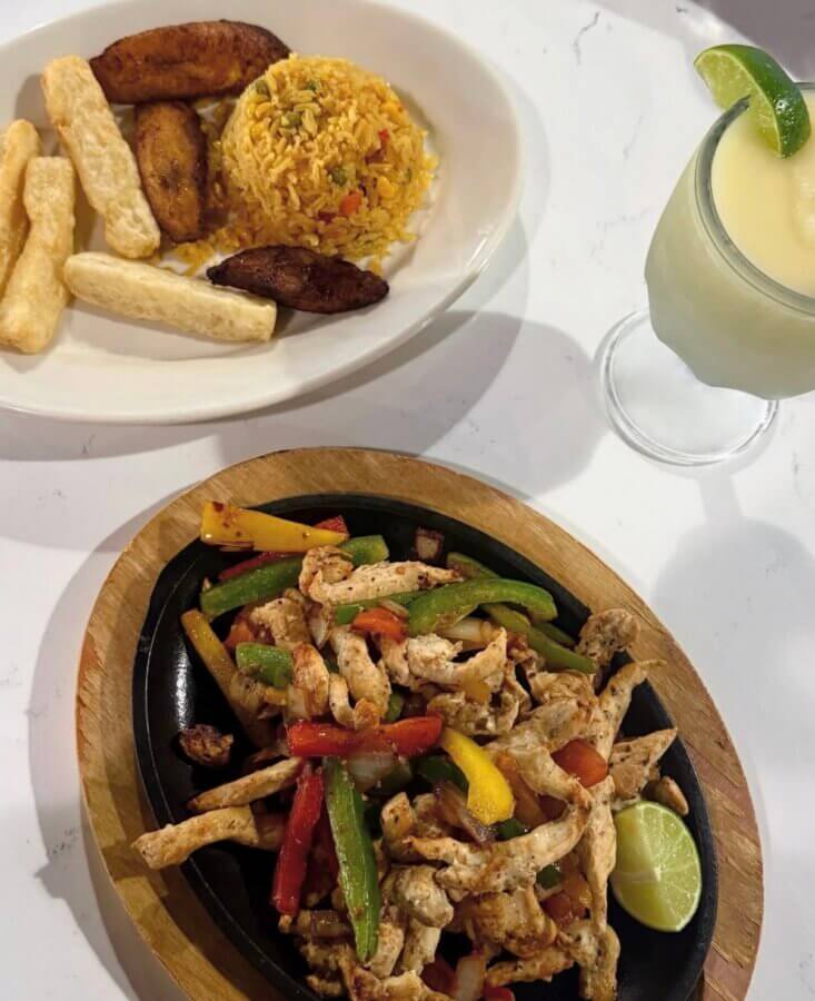 5 New Memphis Restaurants to Try This Month (+ What's Coming Soon!) - 9 A sizzling plate of grilled chicken fajitas with bell peppers and onions, served with a side of rice, fried plantains, yuca fries, and a frozen lime drink.