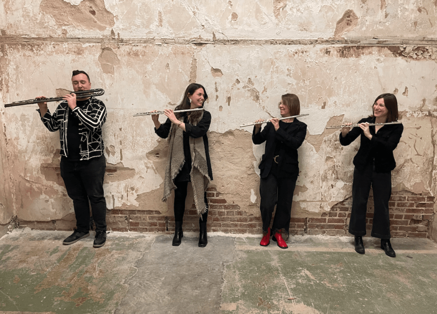Meet the Local Flutist Behind the Memphis Youth Symphony Program - 6 Four people, including Jenny Davis, stand against a worn, textured wall, each playing a flute. They are positioned in a row and facing each other, dressed in dark clothing.