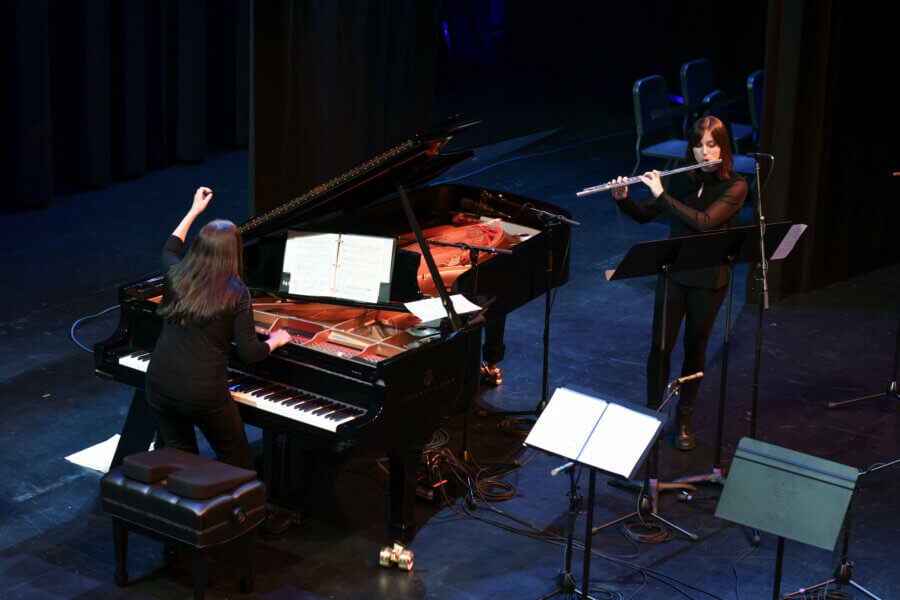Meet the Local Flutist Behind the Memphis Youth Symphony Program - 5 Two musicians perform on stage; one plays the grand piano while the other stands and plays the flute. Sheet music is open on the piano and music stands are nearby.