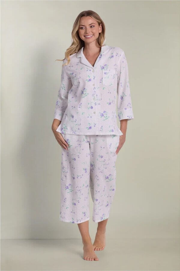 15 Memphis FINDS at Local Shops: Spring Dresses, Home Decor & More! - 7 A woman wearing a matching long-sleeve pajama top and cropped pants with a light purple floral pattern stands barefoot against a plain background, showcasing one of Marchβs cozy Memphis FINDS.