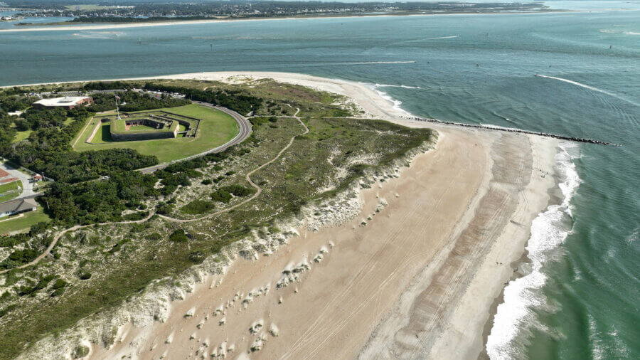 Hidden History in the Southβs Most Beautiful State Parks - 11 Aerial view of a coastal fort in the South, surrounded by green grass, sandy beach, dunes, and ocean waves meeting the shoreβdiscover hidden history in one of the regionβs unique state parks.