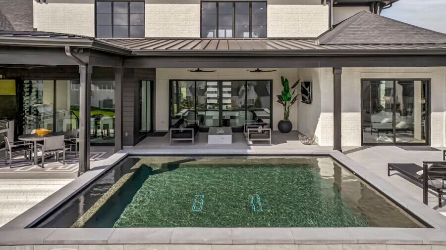 Just Listed! A Custom Williamson County Home Where Indoor & Outdoor Living Shine - 4 Modern custom home with a small rectangular pool, patio seating, and large windows facing the backyard, designed for seamless indoor-outdoor living on a sunny day.