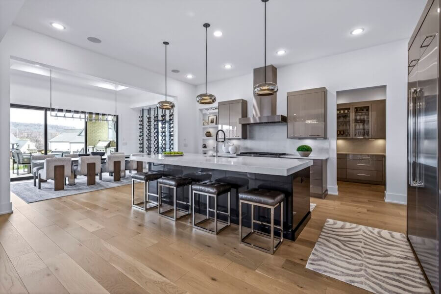 Just Listed! A Custom Williamson County Home Where Indoor & Outdoor Living Shine - 7 Modern kitchen in a Williamson County home with an island, pendant lights, stainless steel appliances, light wood flooring, and an adjacent dining area with large windows for seamless indoor outdoor living.