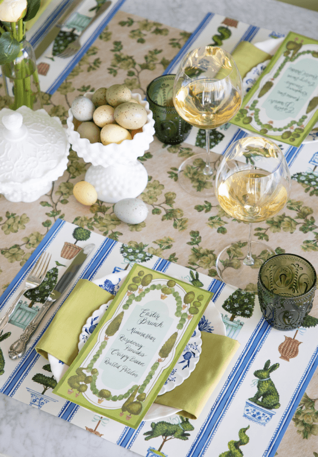 Nashville Steals, Deals & Announcements: April 2026 - 7 A spring-themed table setting with menus, green napkins, wine glasses, a bowl of decorative eggs, and a floral vase on a patterned tablecloth with garden motifs—perfect inspiration for your next Nashville Deals gathering.