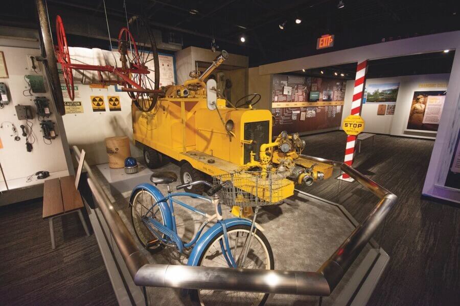 Living History: 7 Tennessee Towns Where the Past Comes Alive - 10 A yellow industrial vehicle and a blue bicycle are displayed in a museum exhibit, reflecting the living history of Tennessee towns, with historical signs and equipment in the background.