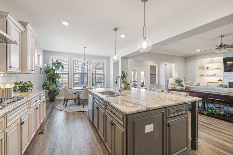 Just Listed! This Nolensville Home is Ready for Summer Entertaining - 7 Modern kitchen in a Nolensville Home featuring a large marble island, pendant lights, stainless steel appliances, and an open layout connecting dining and living areas—perfect for Summer Entertaining with wood flooring and natural light.