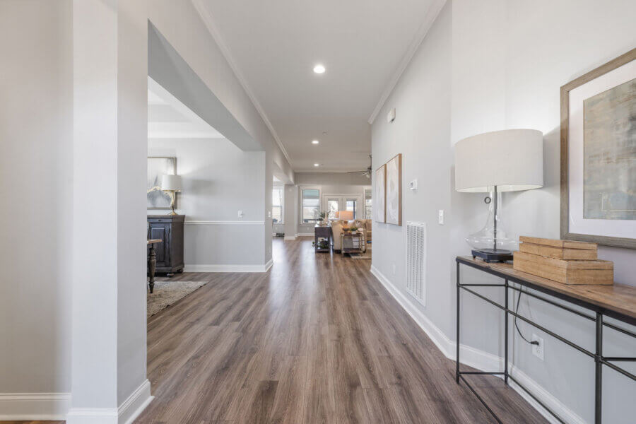 Just Listed! This Nolensville Home is Ready for Summer Entertaining - 3 Bright hallway with wood flooring, a console table with decor on the right, and an open view into a living area with neutral walls and contemporary furnishings—perfect for summer entertaining in this Just Listed Nolensville Home.