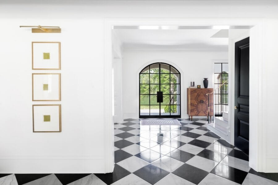 7 Tile Trends Interior Designers Are Loving Right Now - 15 A modern entryway with black and white checkered tile flooring—a nod to current tile trends—large arched window, and minimalist decor on white walls.
