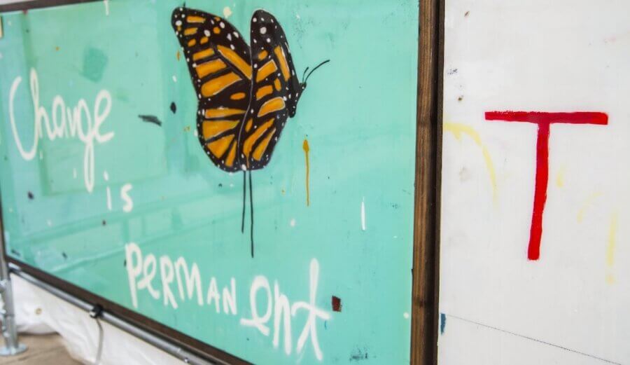 The Best Festivals in the South - 9 A mural of a monarch butterfly with the words "Change is permanent" painted on turquoise; a large red letter "T" is on the adjacent white wall, capturing the vibrant spirit seen at Festivals in the South.