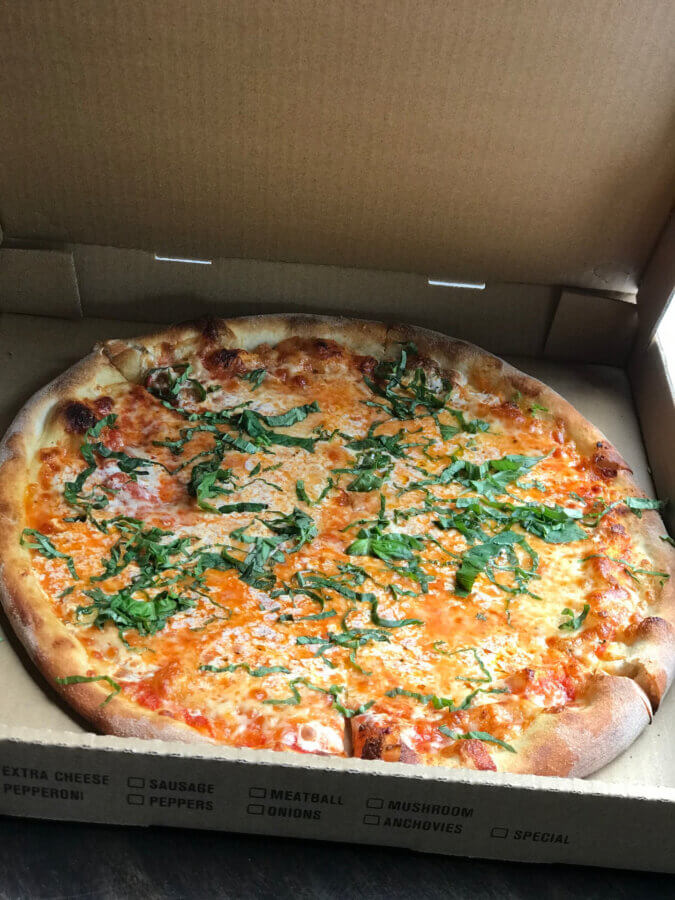 Your Guide to Chattanooga's Culinary Scene - 8 A pizza with cheese, tomato sauce, and fresh basil sits in an open cardboard pizza box on a table in Chattanooga.