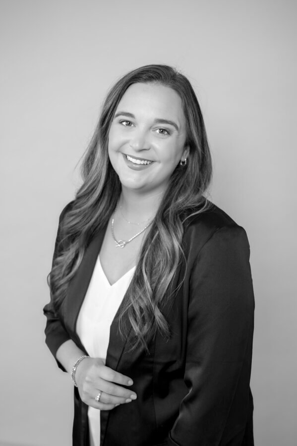 Behind the Scenes with the Director of the Music City Food & Wine Festival - 2 Black and white portrait of a woman with long hair, director of the Music City Food & Wine Festival, wearing a blazer and white top, smiling at the camera against a plain background.