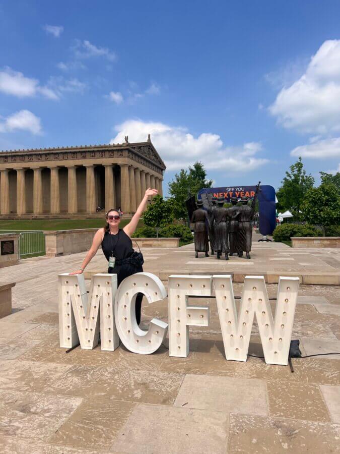 Behind the Scenes with the Director of the Music City Food & Wine Festival - 5 A person poses beside large "MCFW" letters in front of the Parthenon replica in Nashville, with a "See You Next Year" sign highlighting the Music City Food & Wine Festival visible in the background.