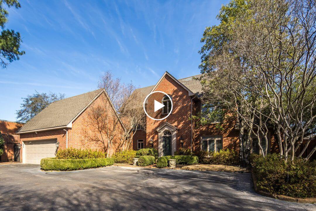 Charming two-story brick house on 2944 Gardens Way in Memphis, featuring a three-car garage, surrounded by trees and landscaped shrubs under a clear blue sky.