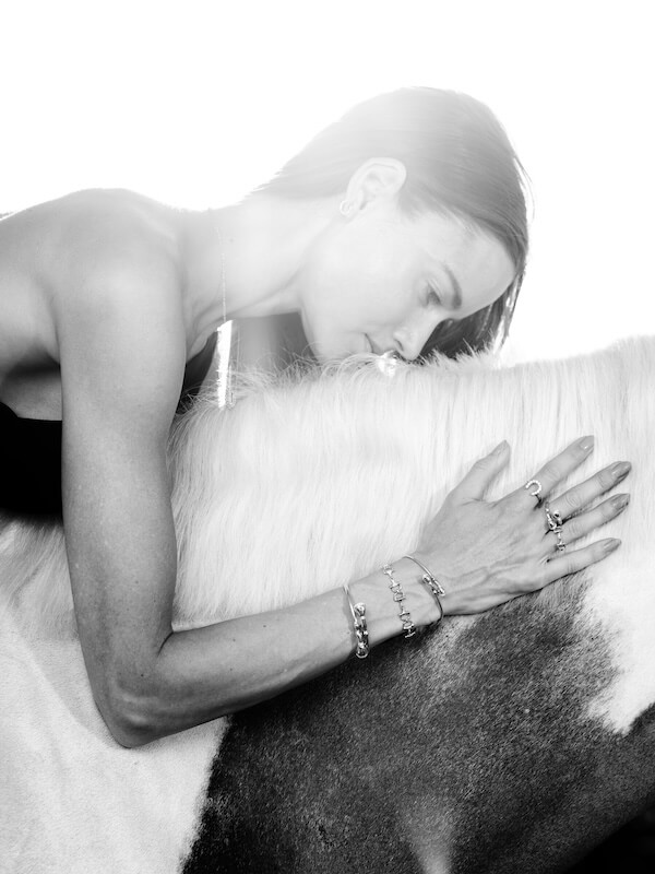 Karina Brez Jewelry: From Florida Horse Country to the Equestrian World Cup Spotlight - 4 A woman in a strapless top, adorned with Karina Brez Jewelry, embraces and kisses the neck of a horse in a striking black and white photograph.