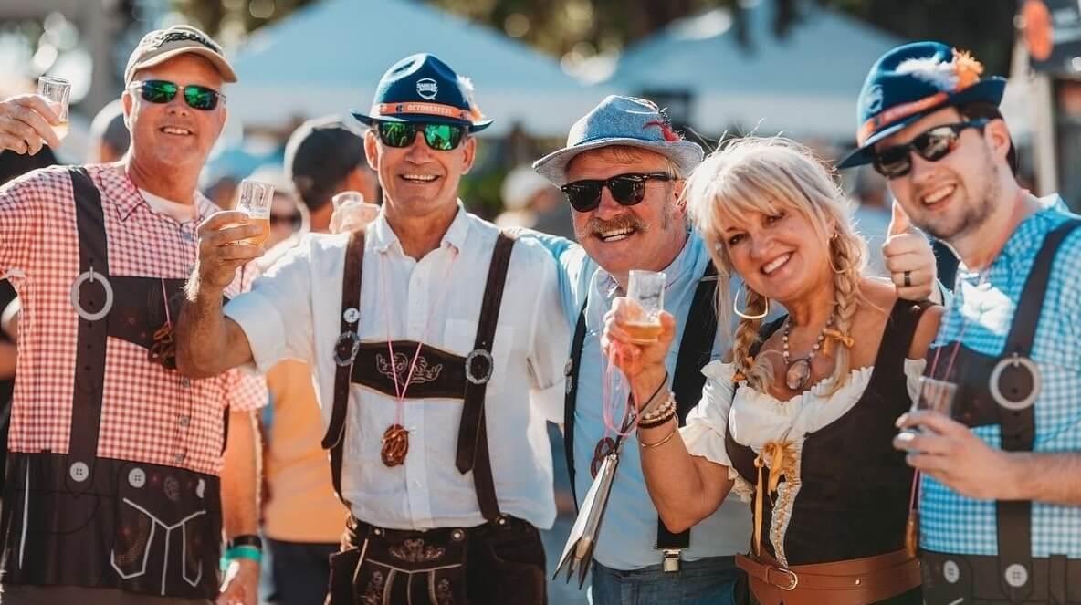 The Best Festivals in the South - 26 A group of people in traditional Bavarian-style clothing and sunglasses toast with beer at one of the best festivals in the south.
