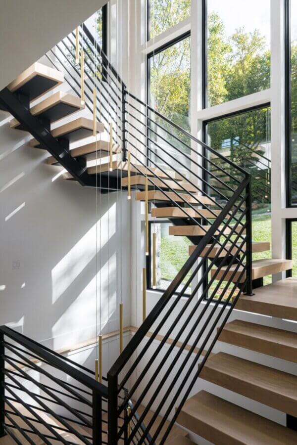 Why the South's Top Home Builders Use C3 Studio - 6 Modern staircase with black metal railings and wooden steps in front of large windows, allowing natural light to fill the space—an ideal feature included in our custom home design services for seamless indoor-outdoor living.