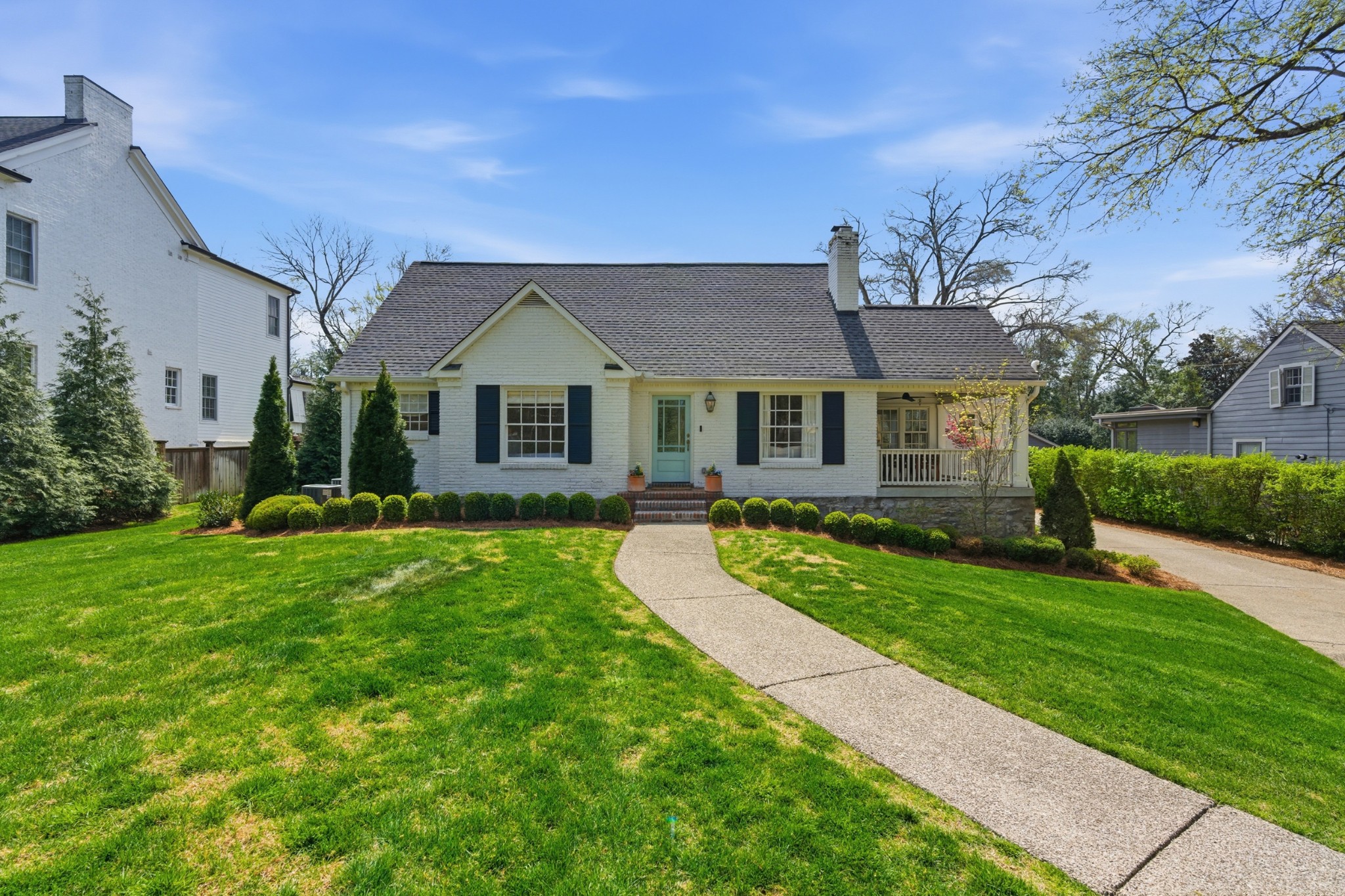 Charming single-story white brick house with a gray roof, front porch, and manicured lawn at 3619 Sperry Ave in Nashville, viewed from the sidewalk on a clear day.