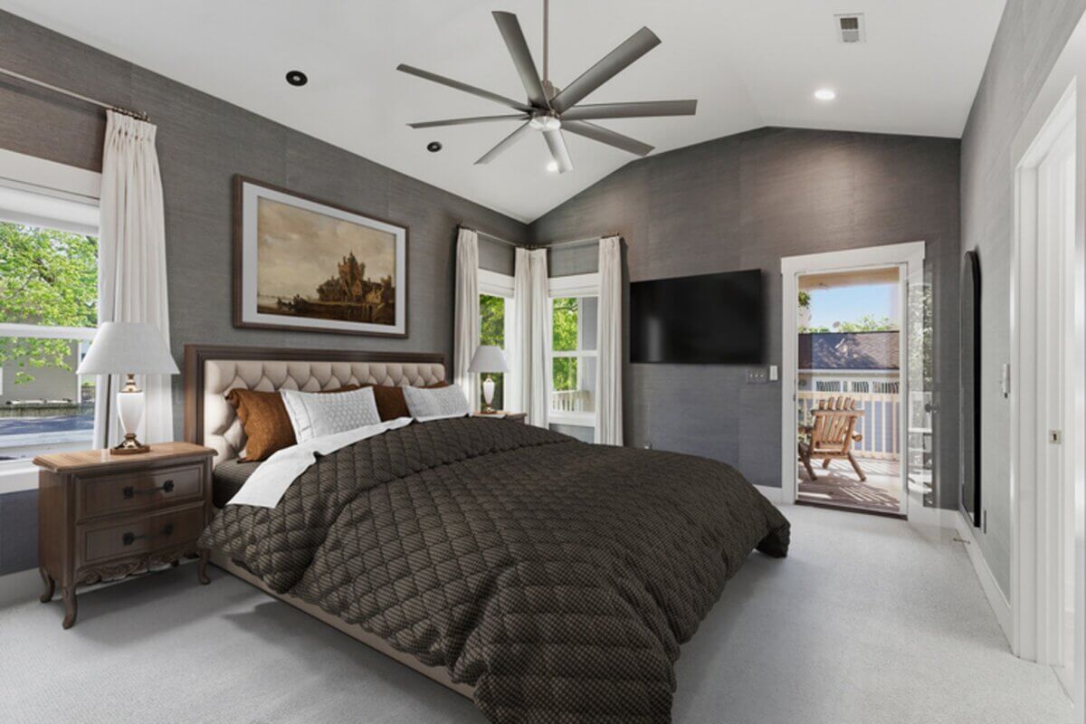 Modern bedroom at 98 44th Ave N with dark bedspread, two windows, wall-mounted TV, ceiling fan, nightstand, and doors leading to a balcony with outdoor furniture.