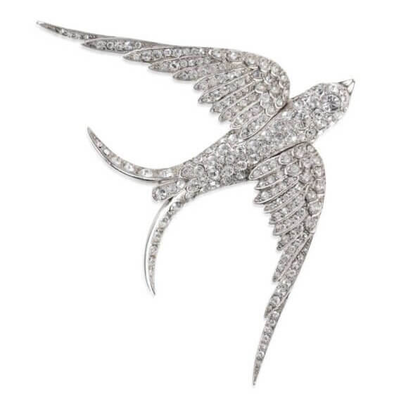 It's the Year of the Brooch! Here's How to Style Them - 10 A dazzling addition to any brooches collection, this jeweled bird features outstretched wings and is encrusted with clear, sparkling stones on a white background.