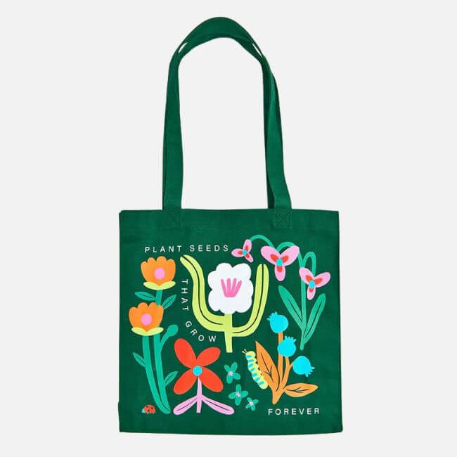 18 Birmingham FINDS for May Celebrations: Graduation, Mother's Day & More - 9 Green tote bag with colorful illustrated flowers and a ladybug, featuring the text "Plant seeds that grow forever." A perfect pick for Birmingham local finds or as a spring accessory for May events.