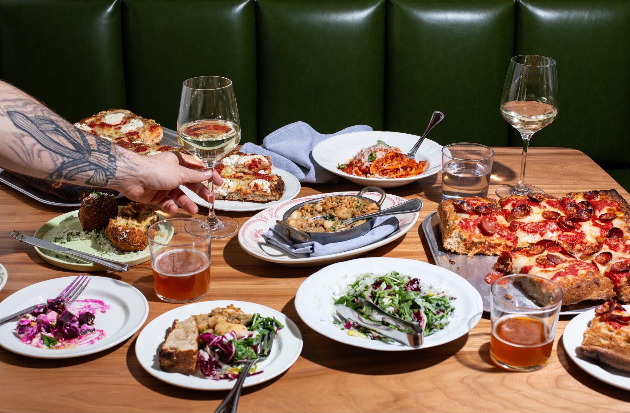 A table with several plates of mouthwatering food laid out along with glasses of wine.