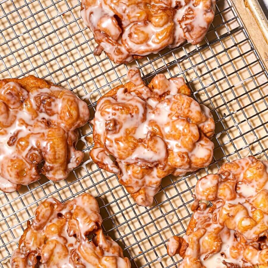 9 New Birmingham Restaurants to Try This Month - 4 Five glazed apple fritters cooling on a wire rack placed over a baking sheet.