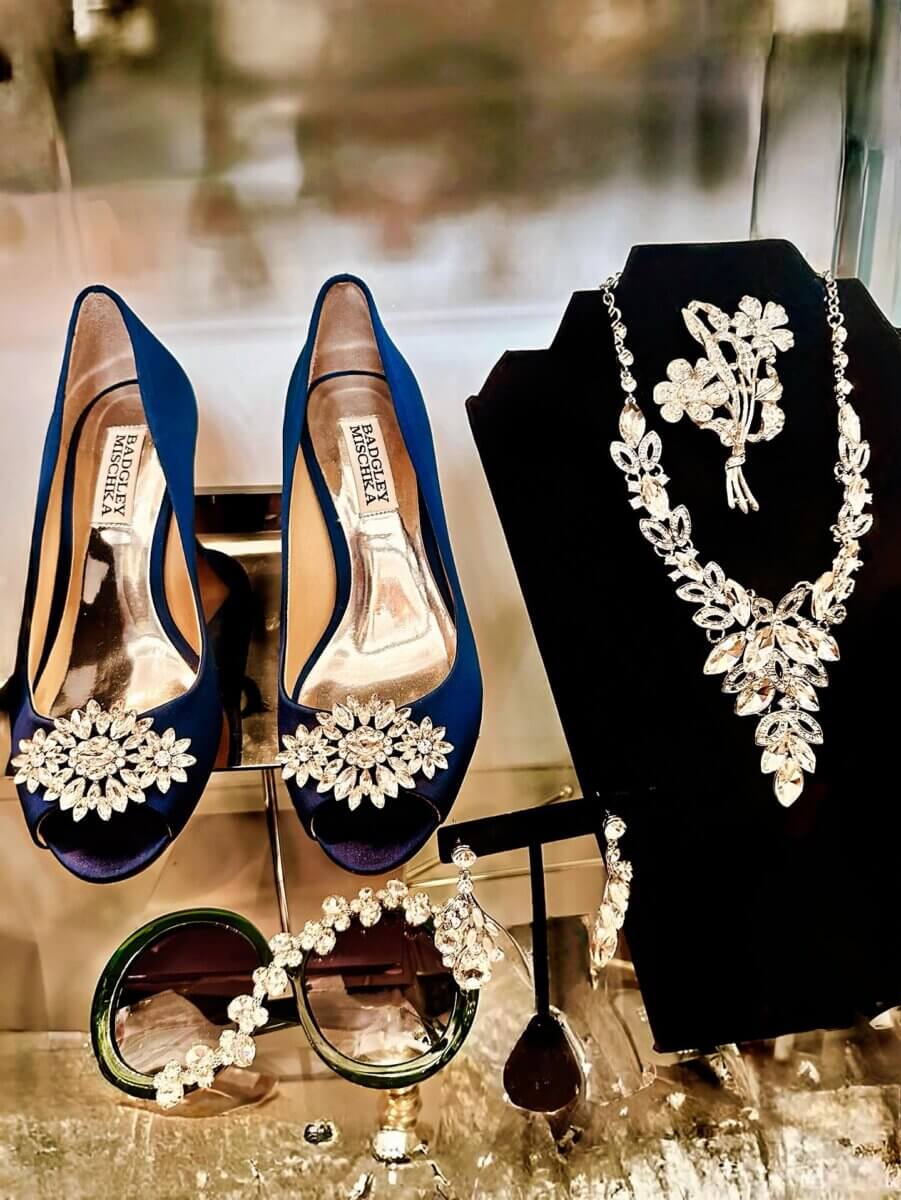 She Curates One of Birmingham’s Top Vintage & Consignment Boutiques - 7 Blue satin peep-toe heels with jeweled embellishments, a silver floral necklace and earrings set, jeweled bracelet, and large dark sunglasses—find these dazzling accessories at vintage boutiques in Birmingham.