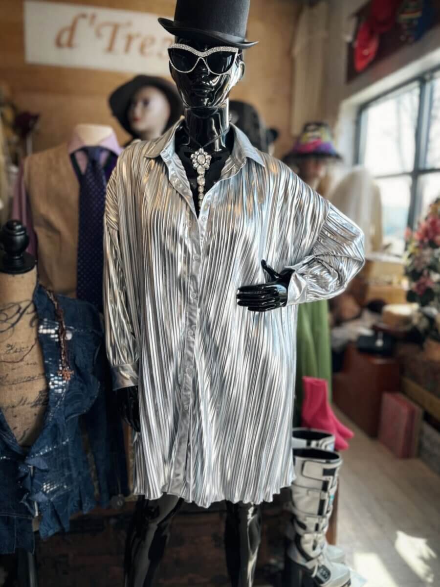 She Curates One of Birmingham’s Top Vintage & Consignment Boutiques - 8 A mannequin dressed in a silver pleated shirt, black hat, and sunglasses stands in a Birmingham vintage boutique, surrounded by other mannequins and curated clothing displays in the background.