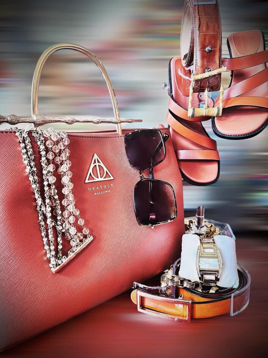 She Curates One of Birmingham’s Top Vintage & Consignment Boutiques - 5 A vintage brown handbag with a gold handle, sunglasses, pearl necklaces, a wristwatch, two brown belts, and brown sandals displayed against a blurred background—perfect for consignment fashion lovers in Birmingham.