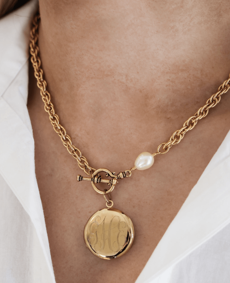18 Birmingham FINDS for May Celebrations: Graduation, Mother's Day & More - 17 Close-up of a gold chain necklace with a round engraved pendant and a single pearl, worn over a white collared shirt—an elegant FINDS piece perfect for May in Birmingham.