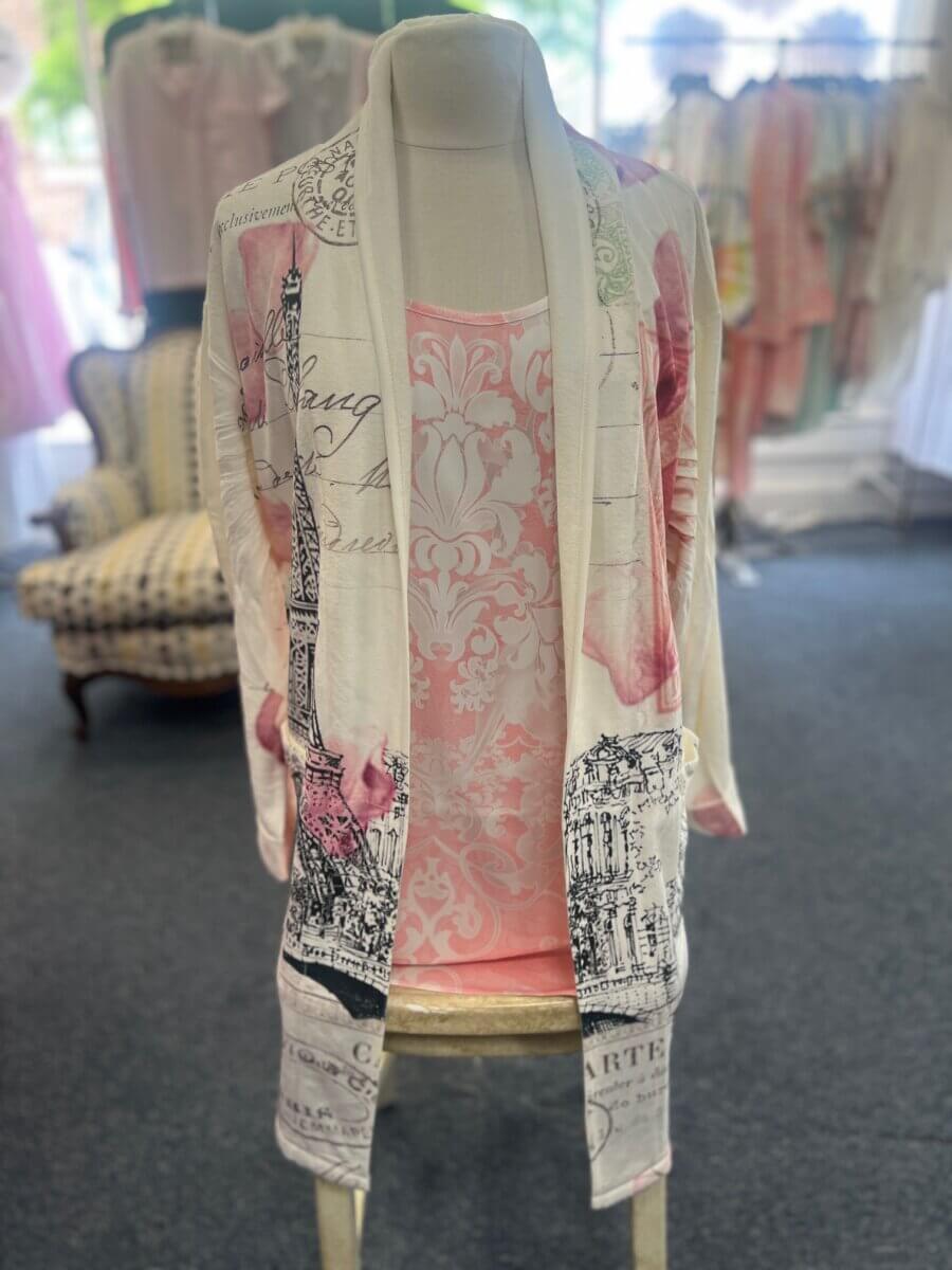 18 Birmingham FINDS for May Celebrations: Graduation, Mother's Day & More - 14 In Birmingham this May, a mannequin displays a light cardigan with Eiffel Tower and script designs over a pink patterned top—perfect for your latest FINDS. Clothing racks and a patterned chair complete the stylish scene.