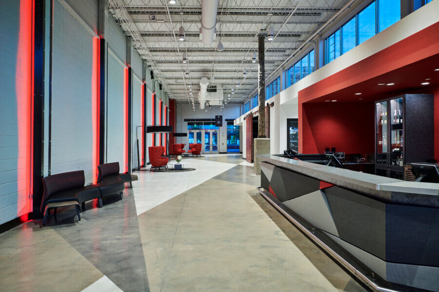 The Birmingham Stage Everyone's Talking About: Inside Red Mountain Theatre - 8 Modern lobby with geometric reception desk, red and black seating, high ceilings, exposed ductwork, and large windows letting in natural light.