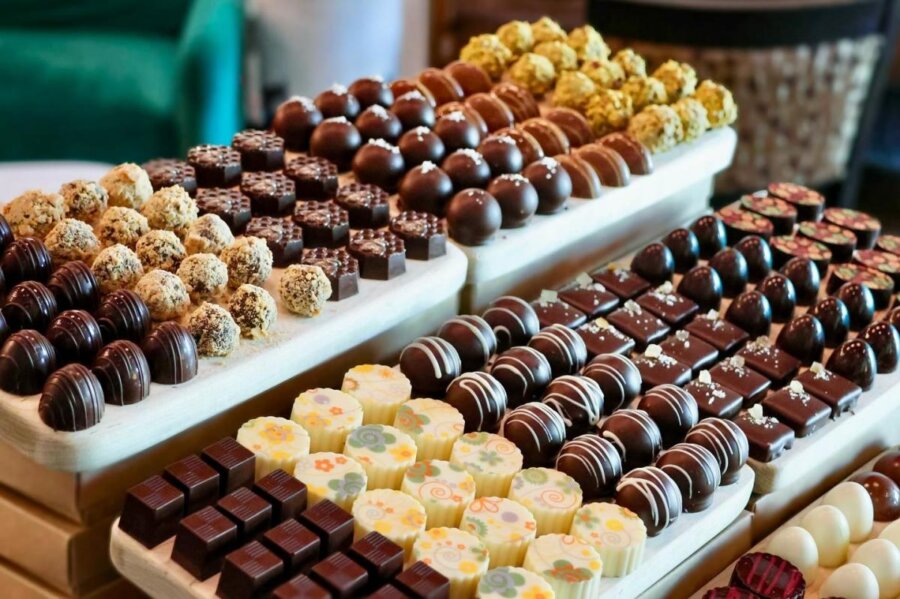 Discover the "Queens of Cuisine," A New Women-Led Culinary Trail in Greenville, SC - 7 An assortment of chocolates and truffles—artfully arranged in rows on wooden trays—celebrates the creativity of the Women in Culinary Trail, featuring various shapes, decorations, and colors.
