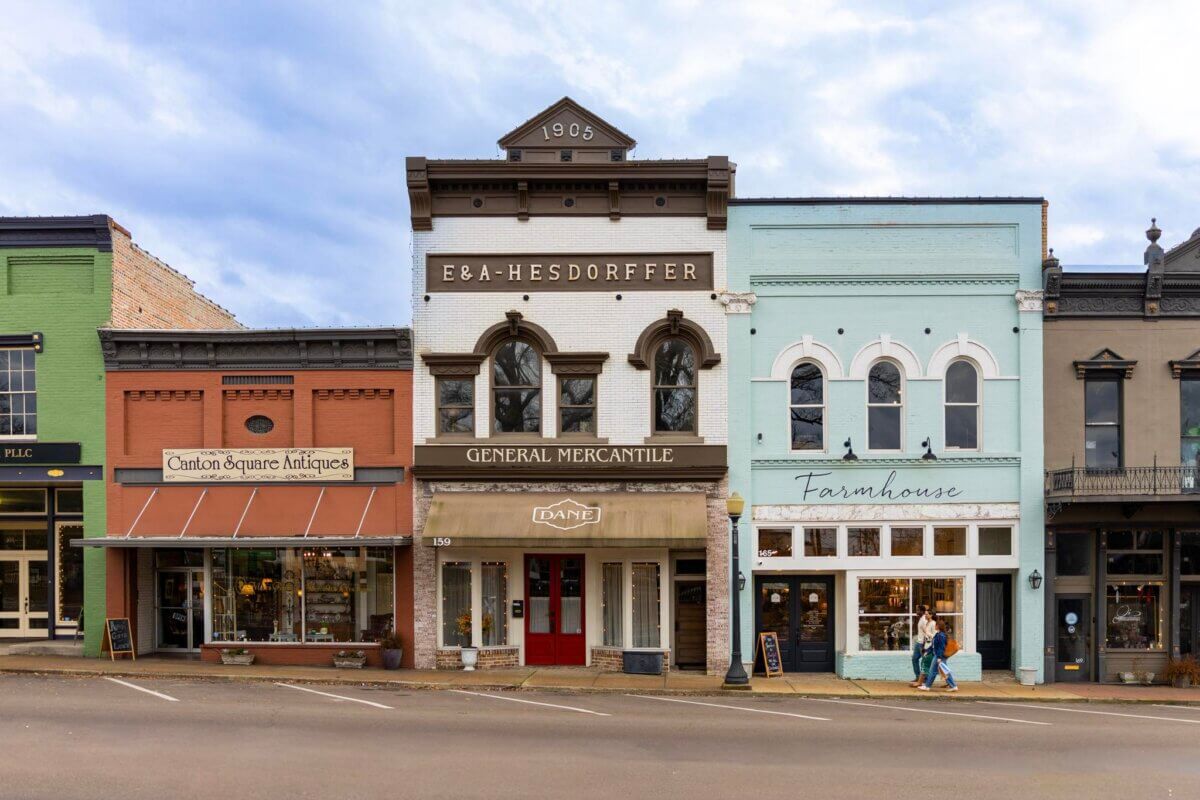 A row of small-town storefronts, including an antique shop and a farmhouse-themed store, lines a quiet street—an inviting scene that captures the charm of kid-tested, parent-approved Southern family vacation destinations.