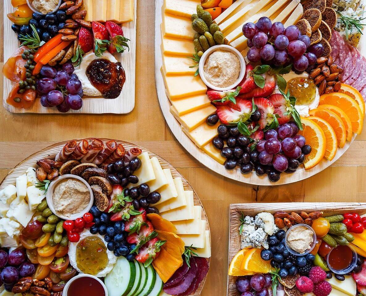 5 New Louisville Restaurants to Try This Month - 5 Four assorted charcuterie boards with cheeses, crackers, fruits, nuts, dips, and vegetables arranged on a wooden table.