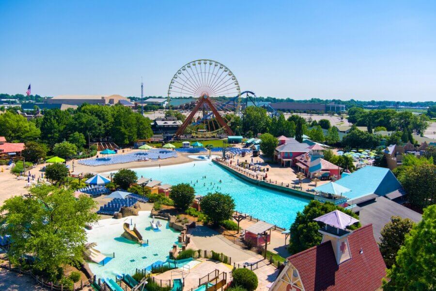 All-Ages Adventure: The Ultimate Trip to Louisville, KY - 5 Aerial view of an all-ages amusement park in Louisville featuring a large Ferris wheel, wave pool, water slides, and various buildings surrounded by trees and parking areas—perfect for a day of adventure.